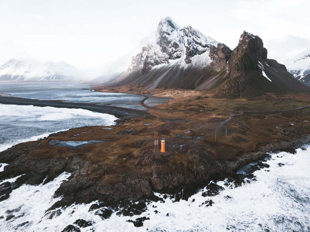 Eystrahorn lighthouse with mountains drone shot